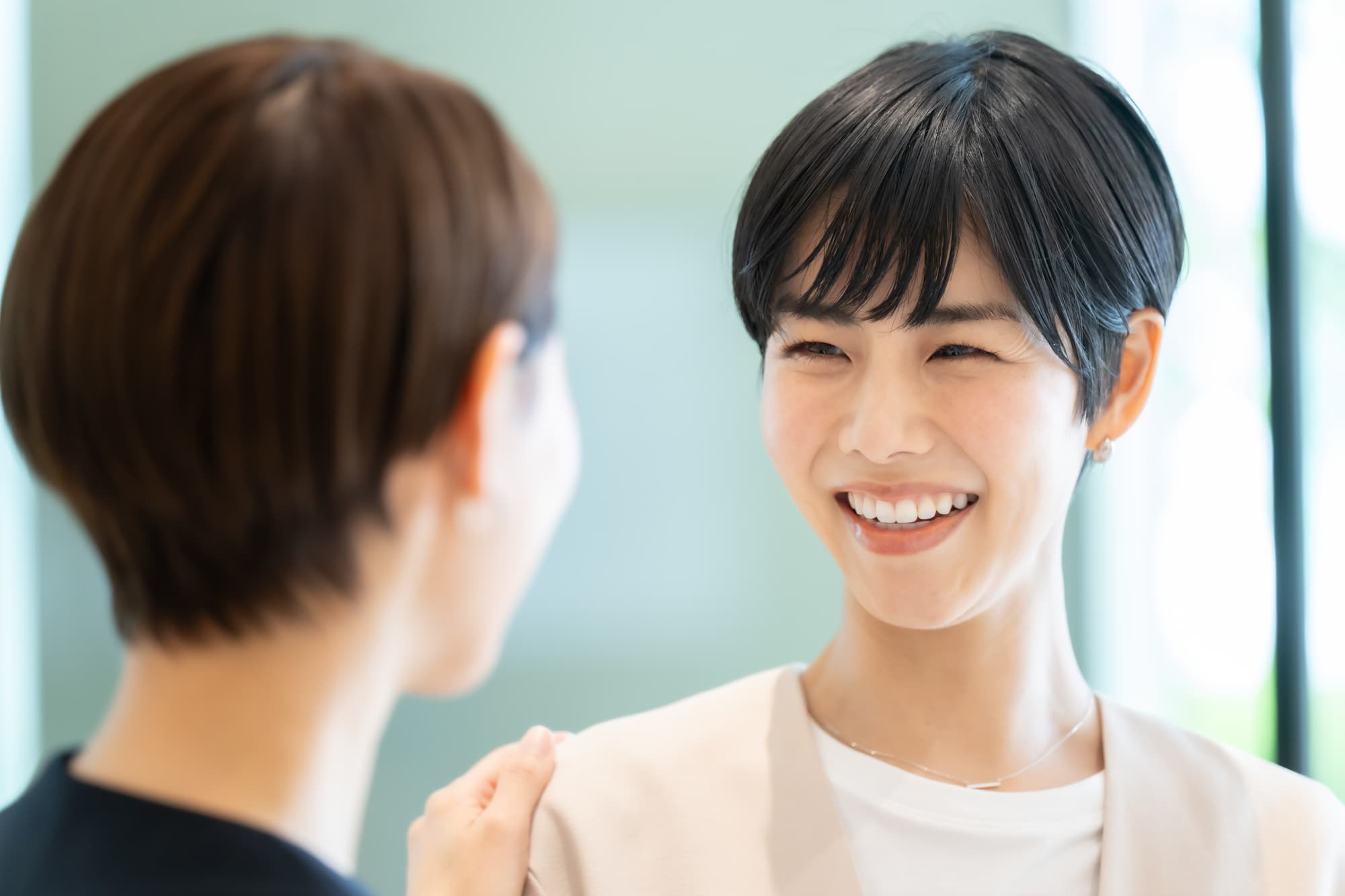 マウスピース矯正をして歯列が整い笑顔で同僚と会話する女性