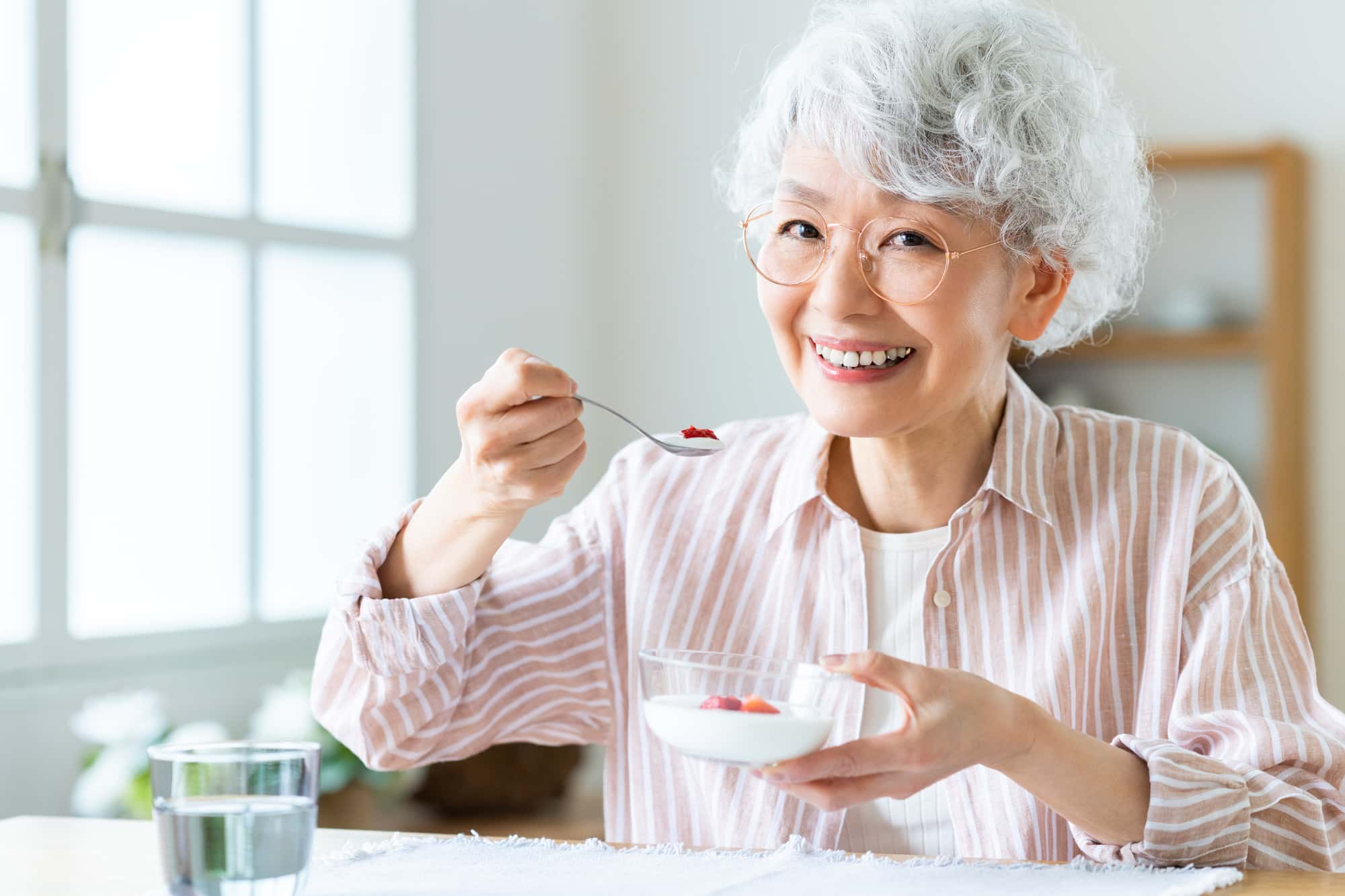  自費の入れ歯で快適に食事をする女性 